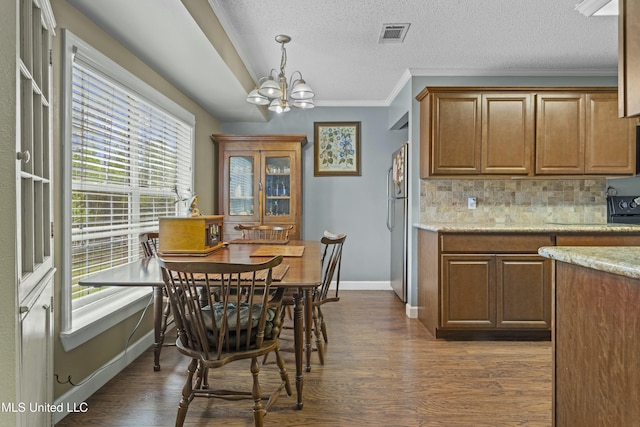 dining space with crown molding, an inviting chandelier, visible vents, dark wood-style flooring, and baseboards