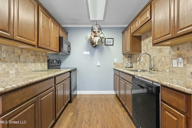 kitchen with a notable chandelier, crown molding, black appliances, a sink, and wood finished floors