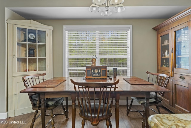 dining room featuring wood finished floors, an inviting chandelier, and baseboards