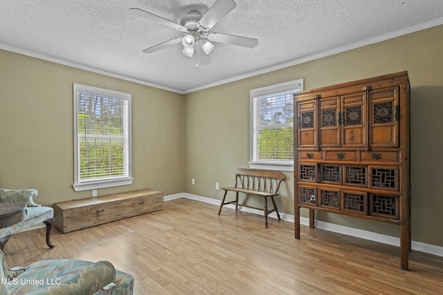 living area featuring crown molding, a textured ceiling, a ceiling fan, wood finished floors, and baseboards