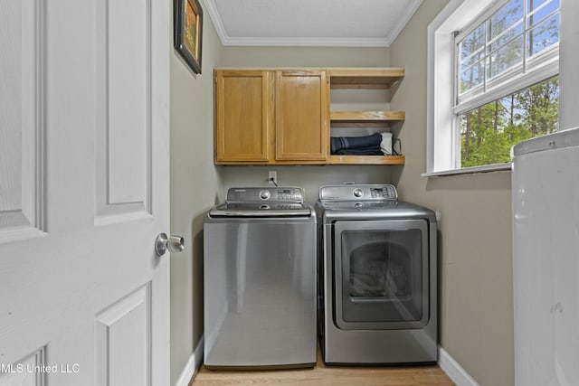 laundry room with baseboards, ornamental molding, light wood-style floors, cabinet space, and washing machine and clothes dryer