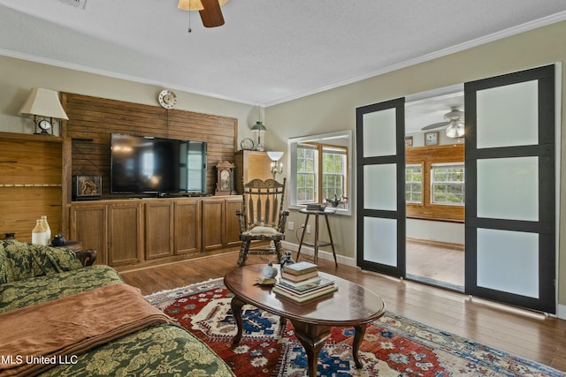 living area featuring crown molding, ceiling fan, and wood-type flooring