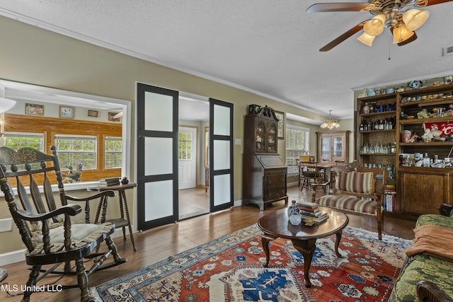 living area featuring a textured ceiling, crown molding, visible vents, ceiling fan, and wood finished floors