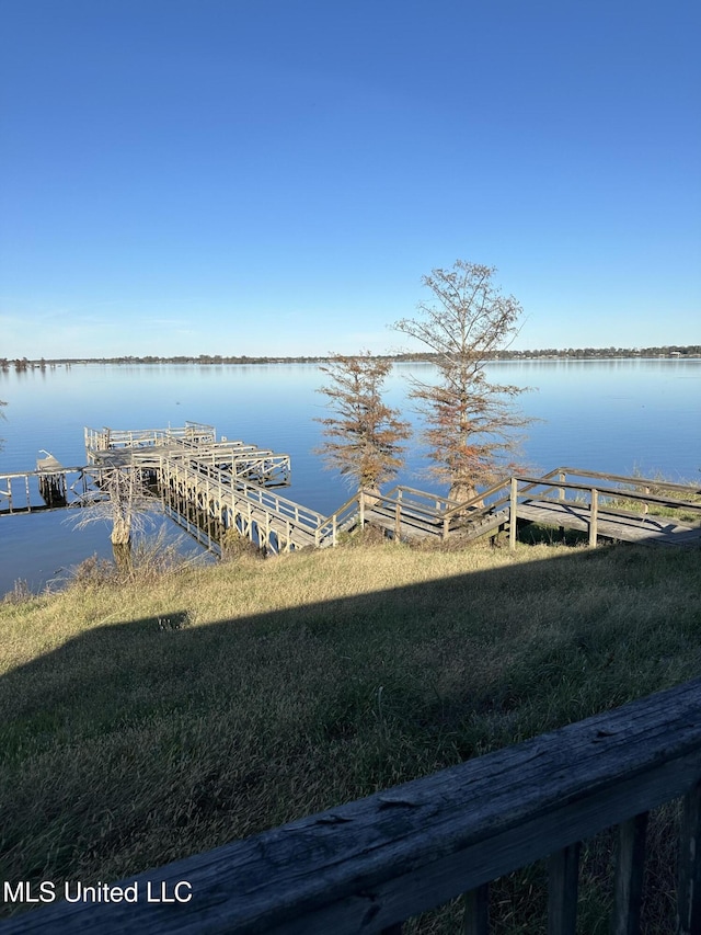 view of dock featuring a lawn and a water view