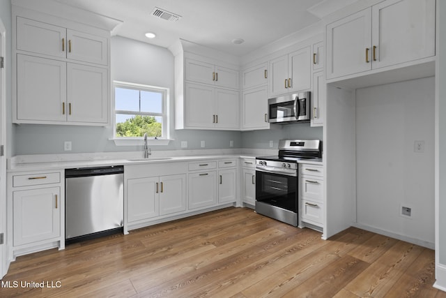 417 4th Ave, Pass Christian, MS 39571 - kitchen featuring appliances with stainless steel finishes, light countertops, white cabinetry, light wood-style flooring, and recessed lighting
