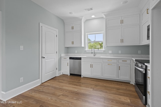 417 4th Ave, Pass Christian, MS 39571 - kitchen with stainless steel appliances, light countertops, white cabinetry, light wood finished floors, and recessed lighting
