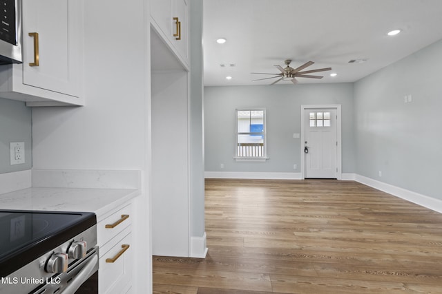417 4th Ave, Pass Christian, MS 39571 - kitchen with white cabinets, a ceiling fan, light stone countertops, stainless steel appliances, and light wood-style floors