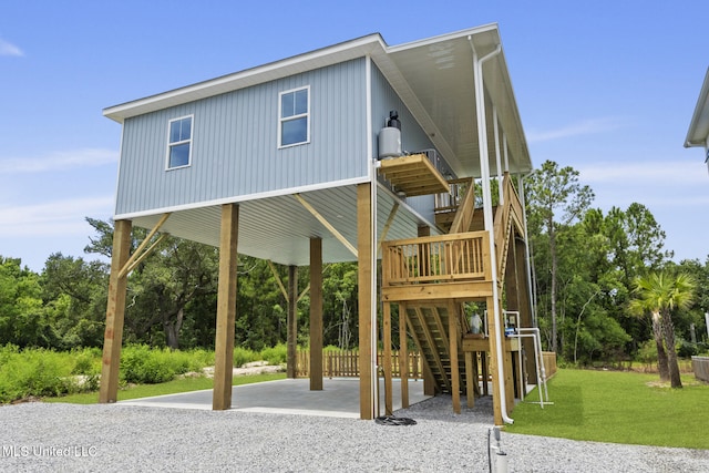 417 4th Ave, Pass Christian, MS 39571 - coastal inspired home with a carport, a front lawn, stairway, gravel driveway, and view of wooded area