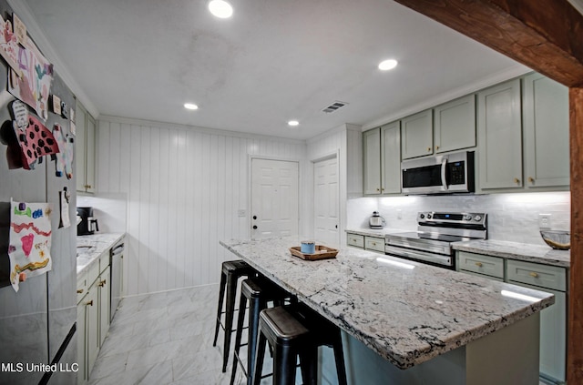 215 Moss Valley Dr, Brandon, MS 39042 - kitchen with stainless steel appliances, light stone counters, a breakfast bar, tasteful backsplash, and recessed lighting