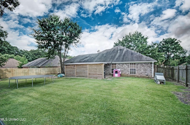 215 Moss Valley Dr, Brandon, MS 39042 - rear view of house with a trampoline, a fenced backyard, brick siding, and roof with shingles