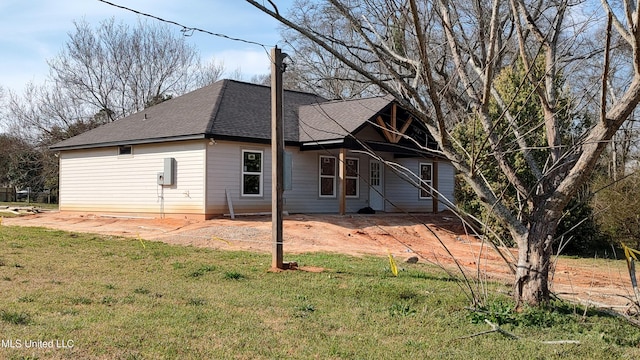 exterior space with roof with shingles and a lawn