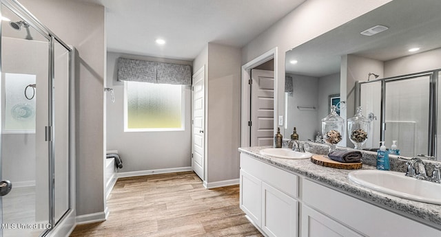 bathroom with a shower with shower door, hardwood / wood-style flooring, and vanity