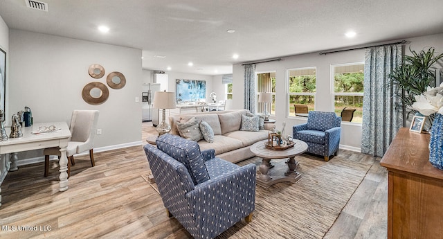 living room featuring light wood-type flooring and a textured ceiling