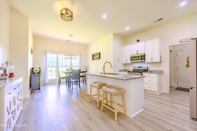 75 Dry Field Cv, Byhalia, MS 38611 - kitchen with appliances with stainless steel finishes, light wood finished floors, white cabinets, light stone counters, and a kitchen breakfast bar