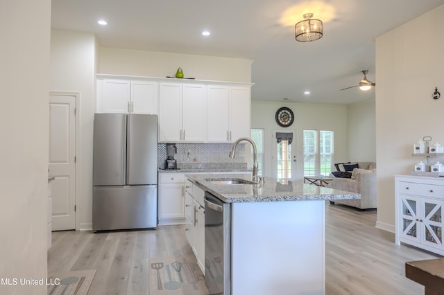 75 Dry Field Cv, Byhalia, MS 38611 - kitchen with stainless steel appliances, light stone counters, light wood-type flooring, white cabinets, and backsplash