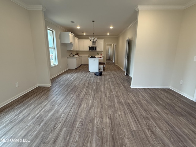 kitchen featuring crown molding, decorative light fixtures, a kitchen island, hardwood / wood-style floors, and white cabinets