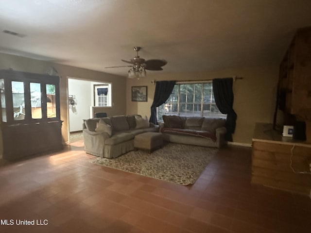 living area featuring visible vents, a ceiling fan, tile patterned floors, and a healthy amount of sunlight