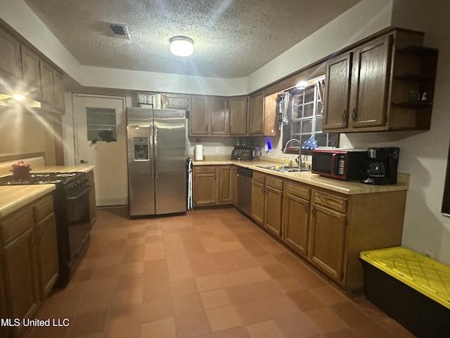 kitchen featuring light countertops, a textured ceiling, black appliances, and a sink