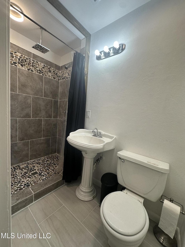 bathroom with a sink, tile patterned flooring, a shower stall, and toilet