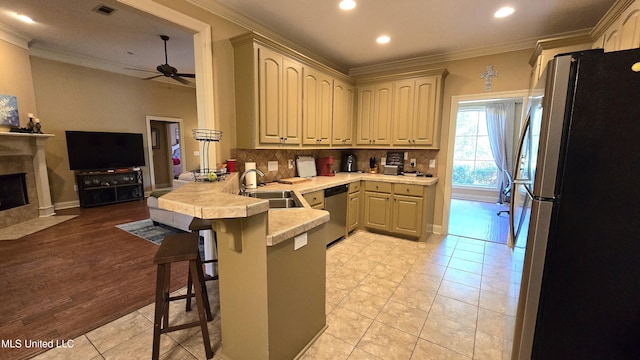 kitchen with a kitchen breakfast bar, kitchen peninsula, crown molding, appliances with stainless steel finishes, and light hardwood / wood-style floors