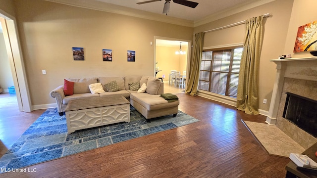 living room featuring dark wood-type flooring, crown molding, and ceiling fan with notable chandelier