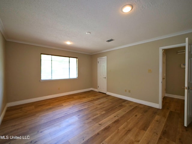 unfurnished room featuring crown molding, wood finished floors, baseboards, recessed lighting, and a textured ceiling
