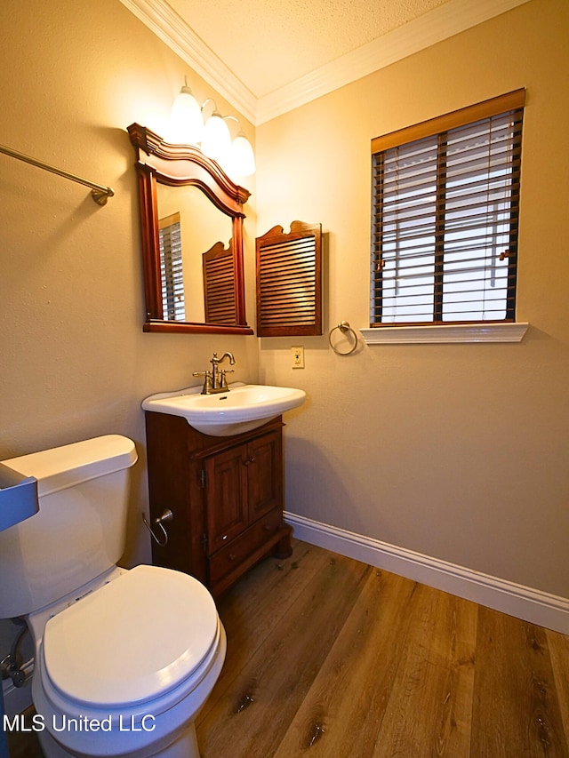 bathroom featuring ornamental molding, wood finished floors, vanity, toilet, and baseboards
