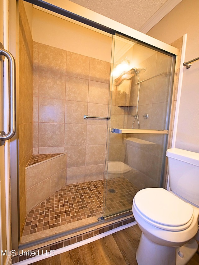 full bath featuring toilet, a shower stall, wood finished floors, and a textured ceiling
