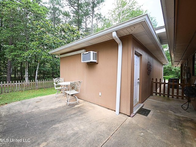 view of outdoor structure with a wall mounted AC and fence
