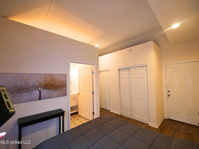 bedroom featuring wood finished floors, two closets, and connected bathroom