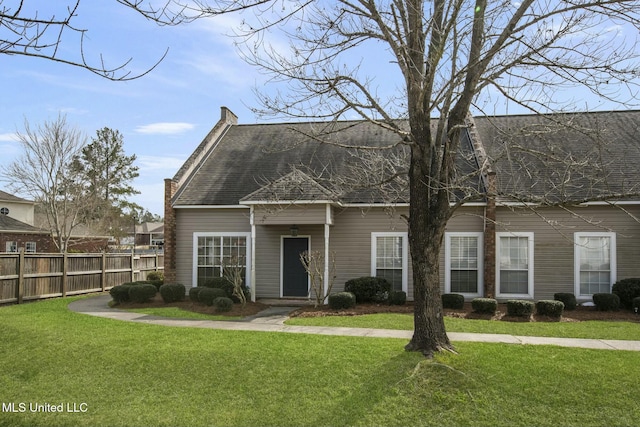 new england style home with a shingled roof, a front yard, and fence