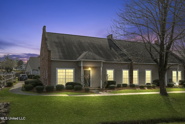 cape cod house featuring a shingled roof, a yard, and fence