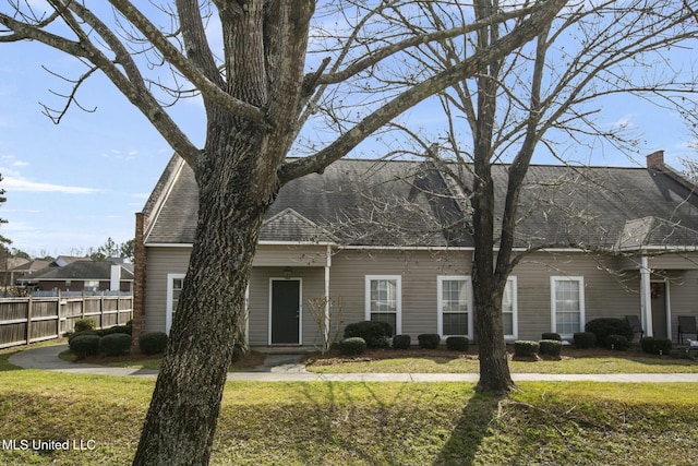 view of front of house featuring a front yard, fence, and roof with shingles