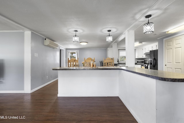 kitchen featuring white cabinetry, an AC wall unit, pendant lighting, and black fridge with ice dispenser