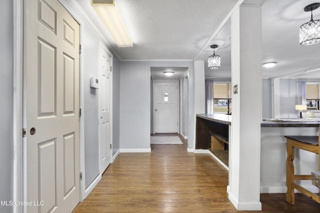 entrance foyer with wood-type flooring, ornamental molding, a chandelier, and a textured ceiling