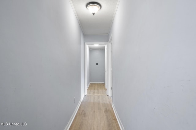 hallway with ornamental molding, a textured ceiling, and light wood-type flooring