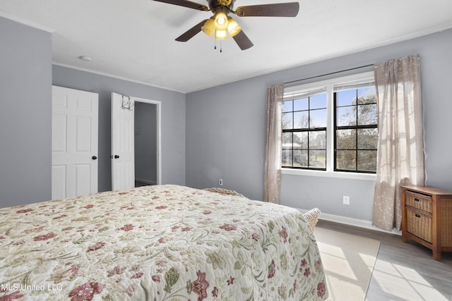 bedroom with ornamental molding, ceiling fan, and light wood-type flooring