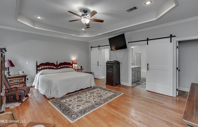 209 Lake Terrace Pl, Brandon, MS 39047 - bedroom featuring a barn door, a raised ceiling, light wood finished floors, recessed lighting, and ensuite bath