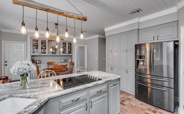 209 Lake Terrace Pl, Brandon, MS 39047 - kitchen with stainless steel fridge, brick flooring, black electric cooktop, light stone countertops, and glass insert cabinets
