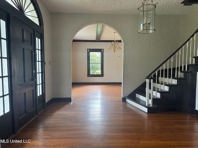 entryway featuring a chandelier, a textured ceiling, and dark hardwood / wood-style floors