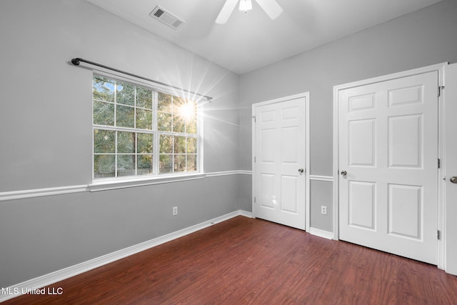 unfurnished bedroom with dark wood-type flooring, multiple windows, and ceiling fan