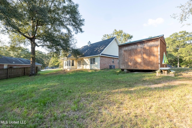 rear view of property featuring cooling unit and a lawn