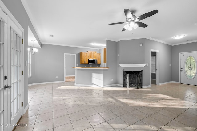 unfurnished living room with ornamental molding, light tile patterned flooring, and ceiling fan with notable chandelier