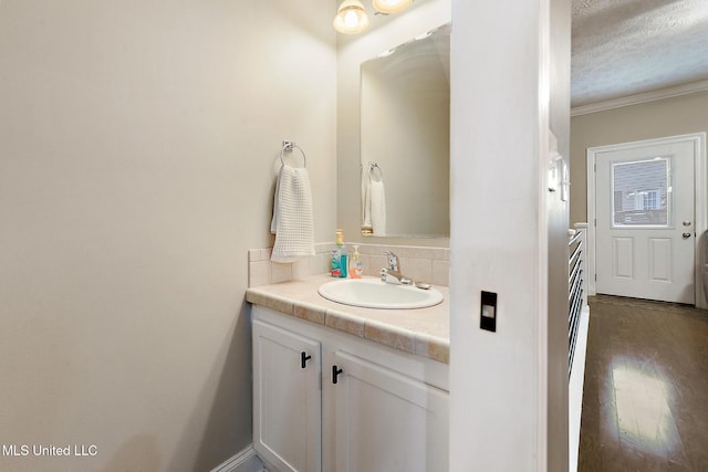 208 E Orchard Loop Unit 208, Diberville, MS 39540 - bathroom with vanity, tasteful backsplash, a textured ceiling, crown molding, and wood finished floors