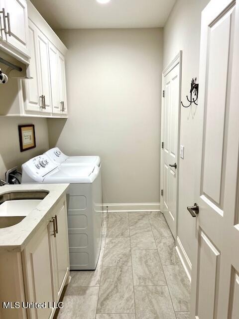 washroom with cabinets, sink, and washing machine and dryer