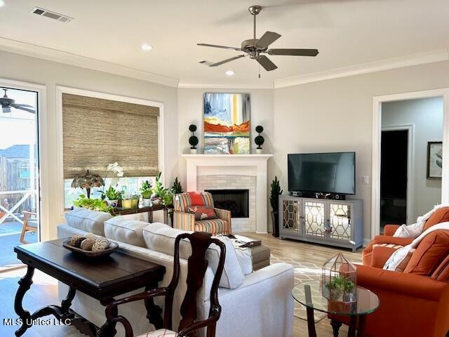 living room featuring ornamental molding, light wood-type flooring, and ceiling fan