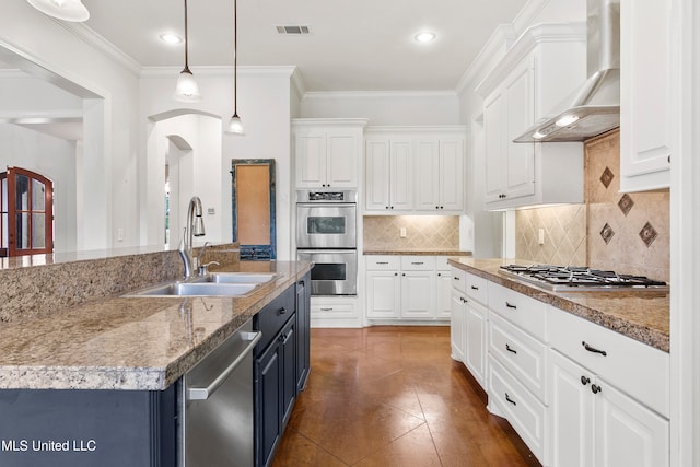 kitchen featuring pendant lighting, white cabinets, sink, wall chimney exhaust hood, and appliances with stainless steel finishes