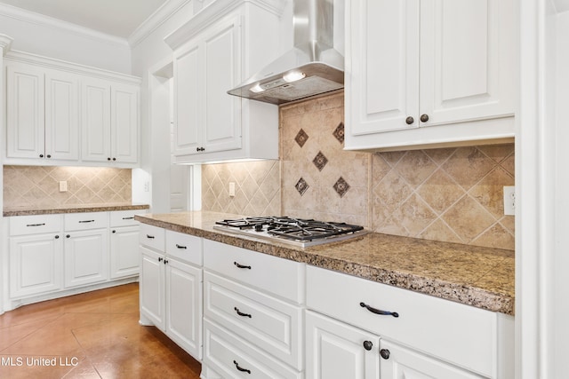 kitchen featuring decorative backsplash, white cabinetry, wall chimney range hood, and stainless steel gas cooktop
