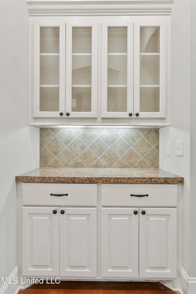 bar featuring decorative backsplash and white cabinetry