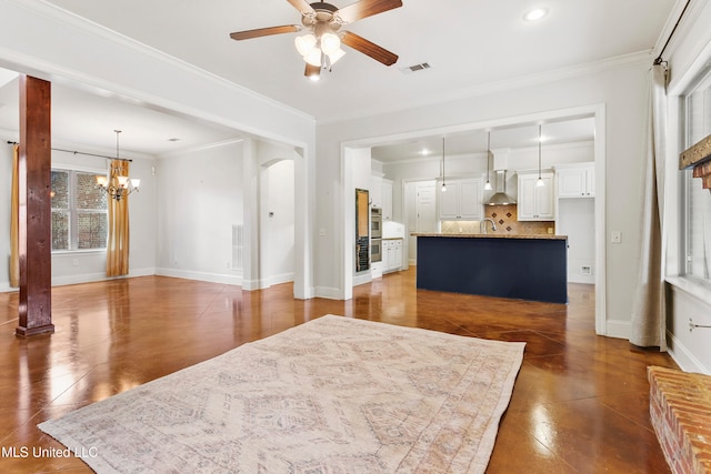 living room featuring sink, ceiling fan with notable chandelier, and ornamental molding